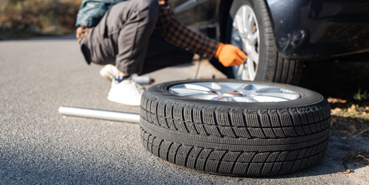 Hombre cambiando de rueda tras una avería en el coche. Transporte, concepto de viaje
